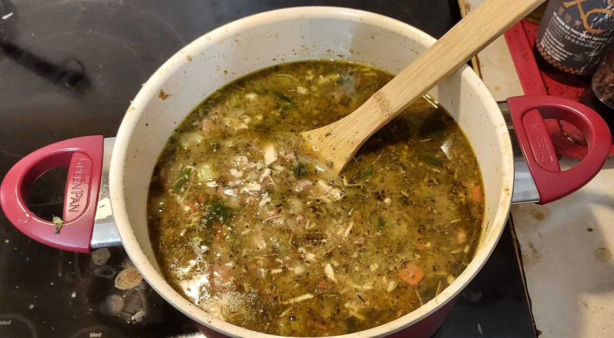 Finished gumbo, the surface flecked with ingredients and a light oil sheen.